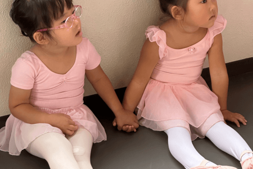 西東京市のコフレダンススタジオでピンクのかわいいバレエレオタードを着て手をつなぐ３歳の女の子2人。