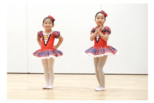 赤いチェックのバレエ衣裳を着て得意げな表情、プリンセス気分の4才と5才の女の子。西東京市コフレダンススタジオの発表会の練習中。