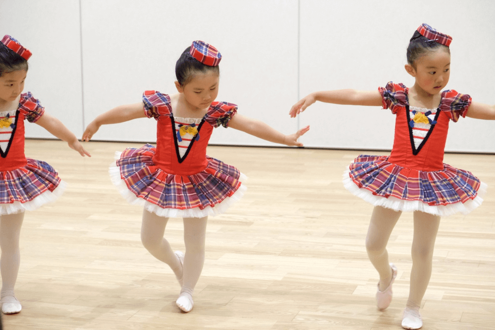 赤いイングリッシュチェックのバレエの衣装を着てお辞儀をする4才の女の子3人