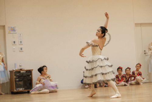 大人のバレリーナが白いフラメンコのような衣装で踊る姿を真剣に見る幼児たち。バレエ発表会の練習の様子。