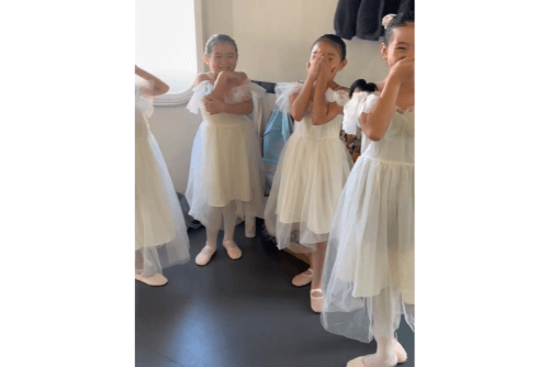 コフレダンススタジオで白いバレエのコスチュームを着て笑う小学生のバレリーナ