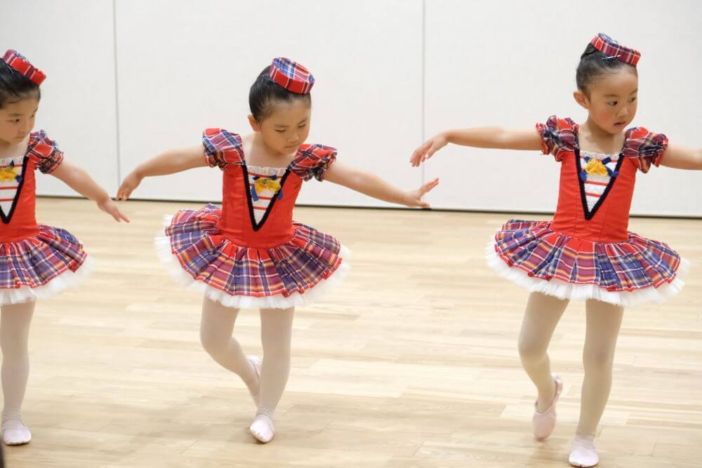 赤いイングリッシュチェックのバレエの衣装を着てお辞儀をする４才の女の子３人